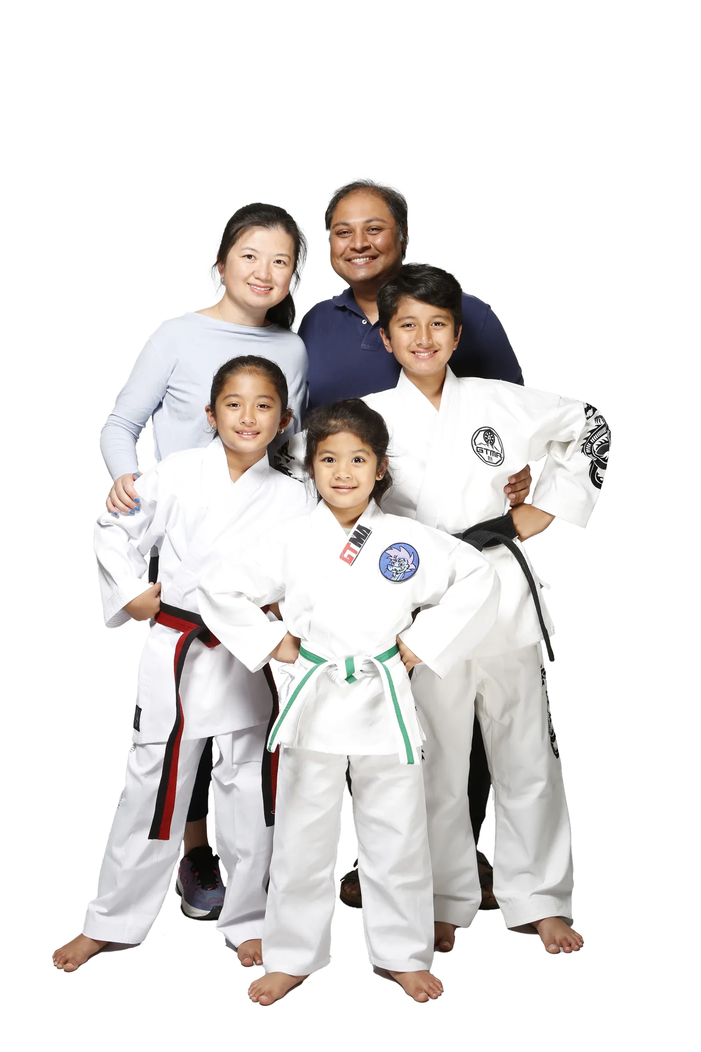 A family of students in white GTMA uniforms - a black belt, a red belt, and a green belt - standing with their parents.