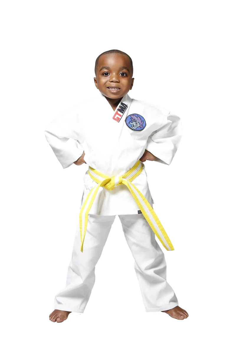A young student in a white uniform with a yellow belt, hands on hips, smiling.